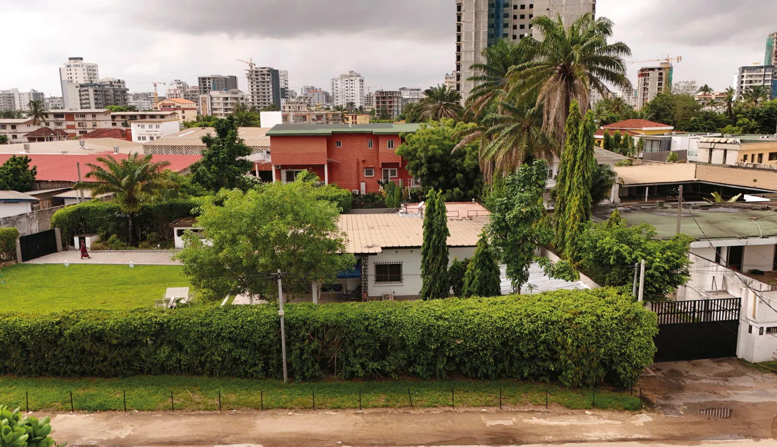 Le terrain du Bietry aujourd'hui, vu depuis la rue : une villa, son jardin et sa haie, les immeubles du quartier derrière